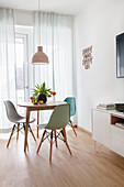 Round table and shell chairs next to window in bright dining room