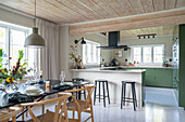 Dining area with classic chairs, open kitchen with counter in the background