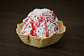 Close up of Spaghettieis ice cream sundae with strawberry sauce in waffle cone cup