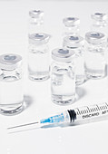 COVID-19-Impfstoffflaschen und Spritze auf weißem Untergrund