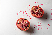 Halved pomegranates with splashes of juice on a white background