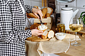 Woman in the kitchen makes sandwiches from baguette and cream cheese