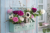 Wall hanging with small spring bouquets of anemones, ranunculus, and cornelian cherry twigs