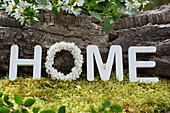 Message HOME with a wreath of lilac blossoms and wooden letters