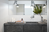 Concrete washbasin decorated with spruce branches in a white bathroom