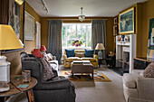 Various seating in sitting room with mustard-yellow walls