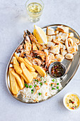 Platte mit Garnelen, Calamari, Pommes, Reis, Saucen und Wein