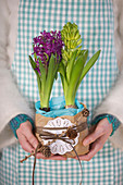 Hands hold hyacinths wrapped in parchment paper