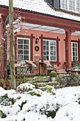 A view from a snowy garden of a veranda with a seating area