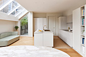 Bright fitted kitchen with island counter, sofa and skylight