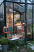 Stuhl mit Apfelkranz vor weihnachtlich dekoriertem Wintergarten