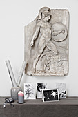 Christmas cards on console table below antique Greek relief on wall