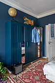 Petrol-colored armoire with mirrored doors in the bedroom with blue walls