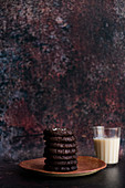 Schokoladenplätzchen auf Teller, dahinter ein Glas Hafermilch