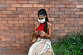 Young woman in facemask using smartphone