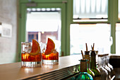 Two negroni cocktails in glasses on a bar countertop