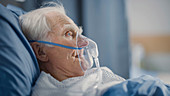 Man wearing oxygen mask in hospital bed