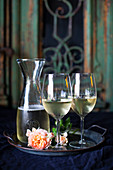 Stillleben mit Weißwein in Karaffe und Gläsern auf Tablett