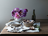 Pilze in Holzschale mit Knoblauch, Geweih und Blumen auf Holztischplatte