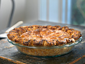 Pie with flakey crust cooling on a wooden table