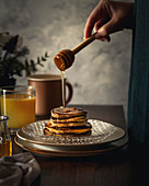 Frau träufelt Honig auf Pancake-Stapel