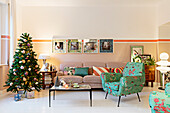 Retro armchair with colorful upholstery, coffee table, sofa, and Christmas tree in the living room