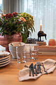 Cutlery, glasses, ceramicware, and bouquet of flowers on dining table
