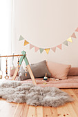 Indoor play area with baby's activity centre on fluffy fur rug and bunting