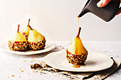Poached pear with chocolate and granola, drizzled with syrup