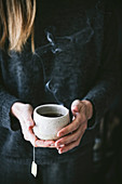 A woman holding a cup of black tea