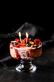 Eis-Trifle mit Himbeeren, Heidelbeeren und brennenden Kerzen