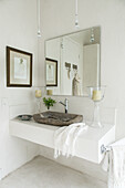 Weißer Waschtisch mit rustikalem Waschbecken, darüber Spiegel im Badezimmer