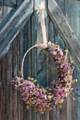 Door wreath with carnations, ranunculus flowers, sea lavender, cornelian cherry, and catkin willow