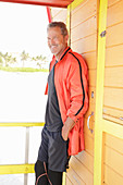 Grauhaariger Mann in schwarzer Sportbekleidung und roter Jacke