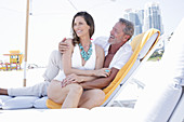 A middle-aged couple wearing beach clothing on a sun lounger