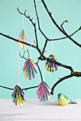 Folded paper Easter eggs hanging from branch