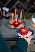 Hand holding a plate with a candy apple