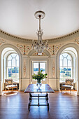 Decorative entrance room with glass chandelier above marble table in 18th century mansion