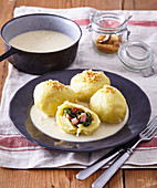 Potato dumplings with smoked meat and spinach filling and horseradish sauce