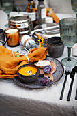 Herbstlich gedeckter Tisch mit Kürbissuppe und Pflaumen