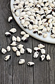 Black and white beans seeds in plate on old wood table