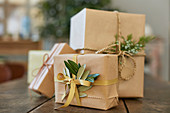 Gifts wrapped in brown paper with olive leaves and juniper sprigs