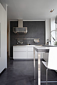 White cupboard and counter with bar stools in kitchen with concrete floor