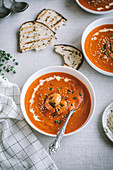 Sweet pepper and spicy shrimp soup served with toasted bread on linen cloth