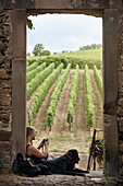 Woman and dog resting, vineyard on background