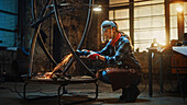 Sculptor polishing a metal tube sculpture with grinder