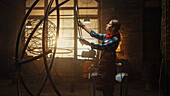 Sculptor fitting a metal ring to a tube sculpture