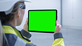 Engineer using a tablet with a green screen