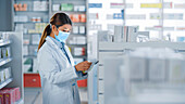 Pharmacist wearing a face mask using a tablet
