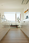 Küche mit weißen Hochglanzfroten, Blick auf Sitzbank mit Kissen